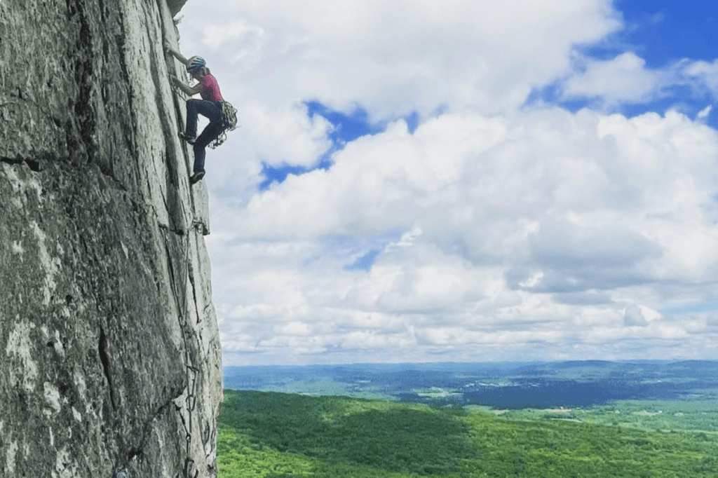 A man climbing up the side of a rock wall.